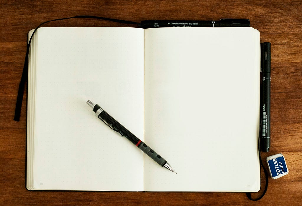 An open notebook with blank pages and a pen on top.