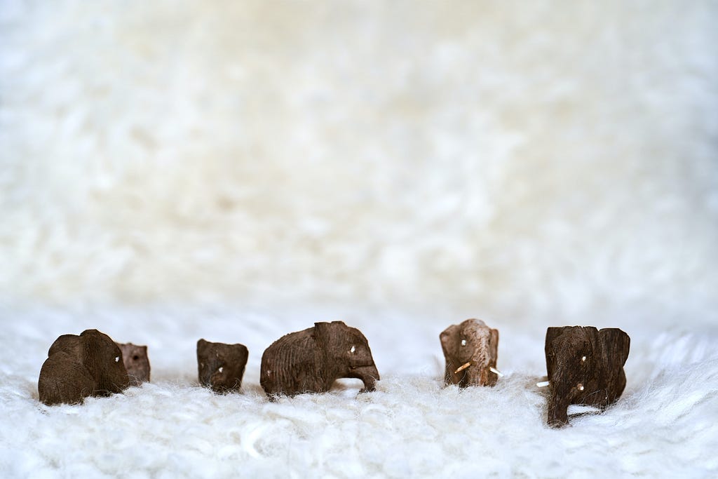 a photograph of five tiny wooden carved elephants