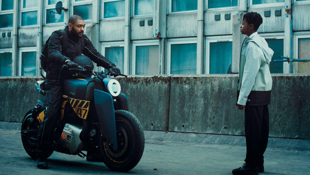 A boy blocks the path of a motorcycle rider.