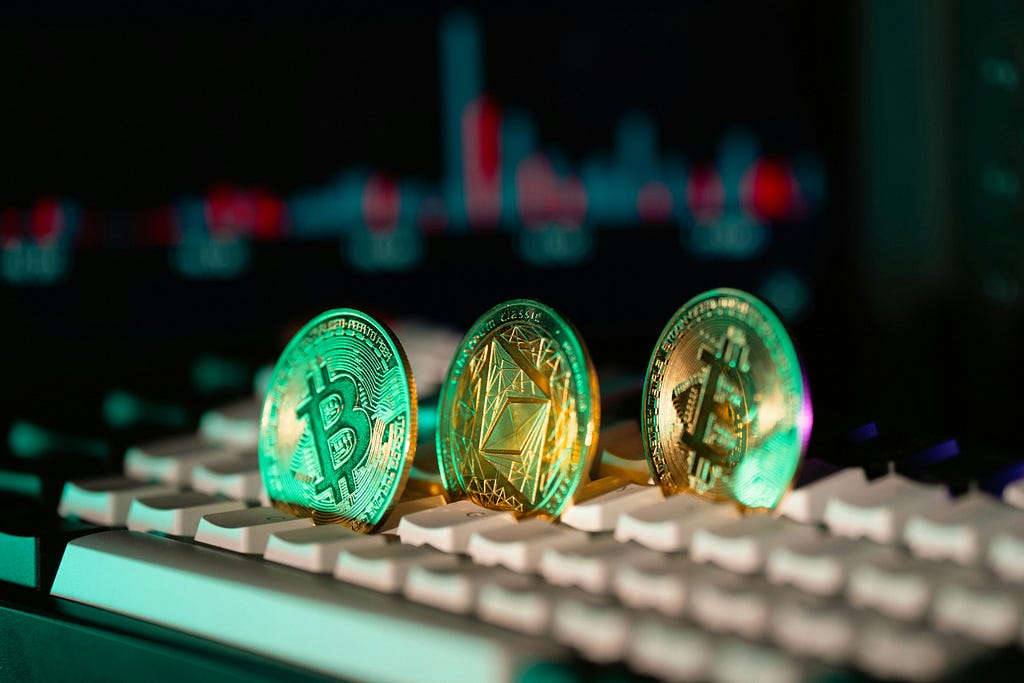 Bitcoin coins on computer keyboard with trading chart in background