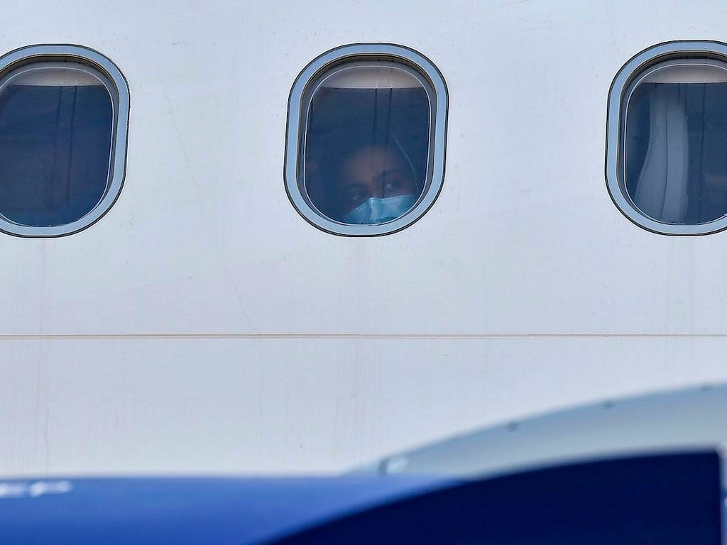 A person peers out the window of a plane.