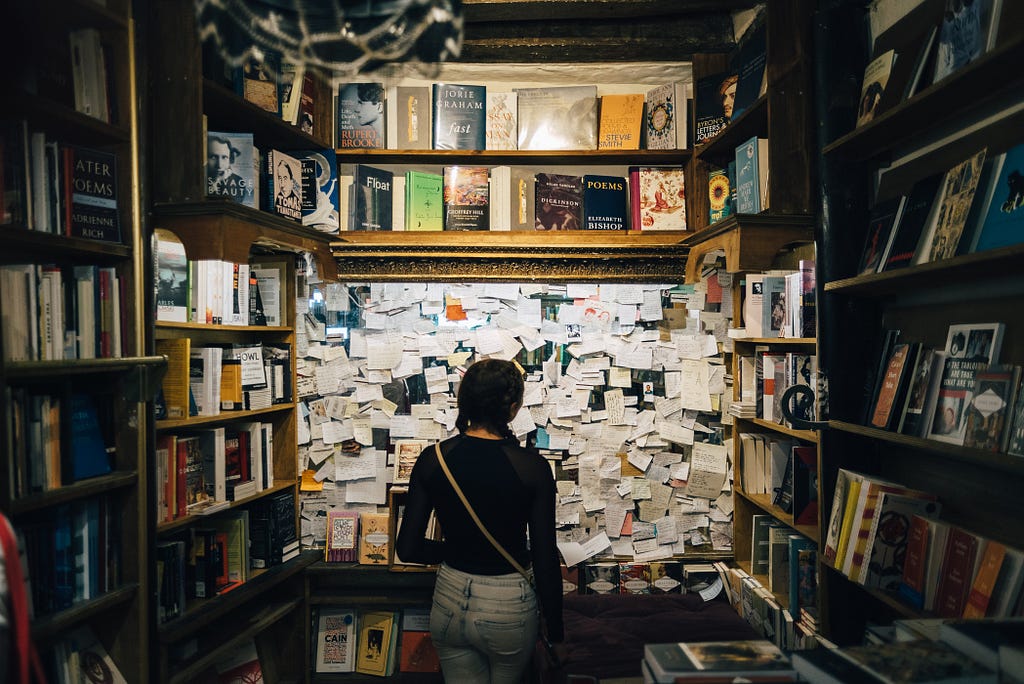 Menina diante de um quadro com inúmeros post-its. Tal imagem remete à necessidade de tomada de decisões diante de tantas opções disponibilizadas.