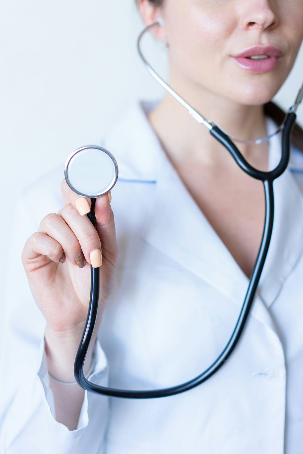 A lady doctor holding up a stethoscope towards the viewer