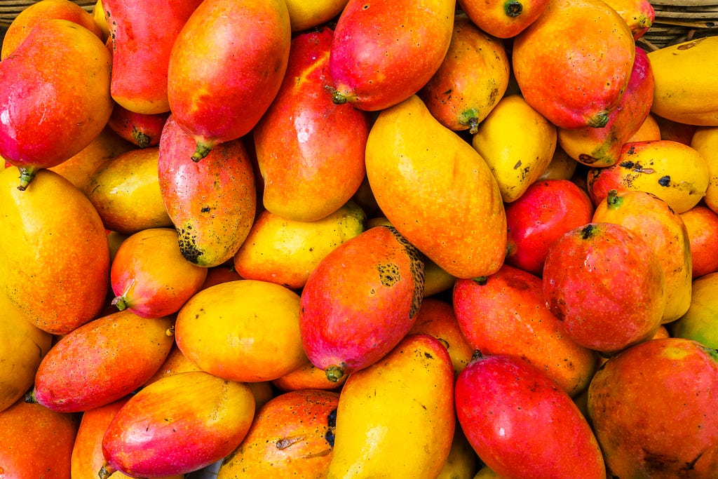 A pile of many brightly colored mangos.