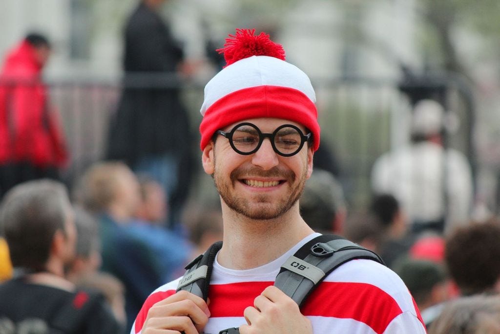 A smiling man dressed as Waldo from “Where’s Waldo”
