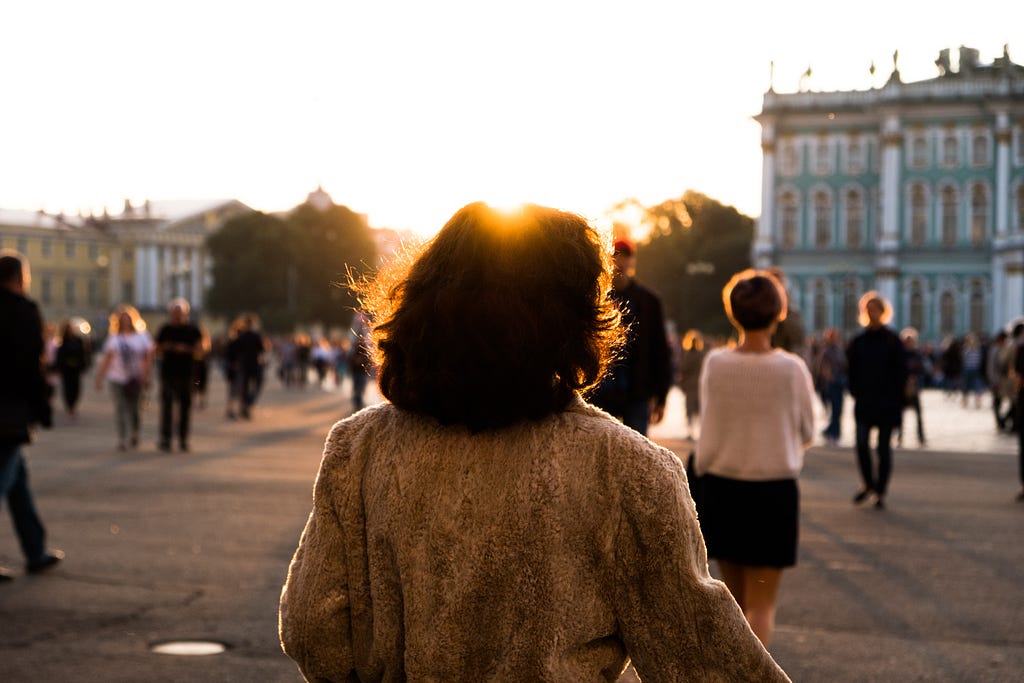 The back of a woman in European town square with evening light