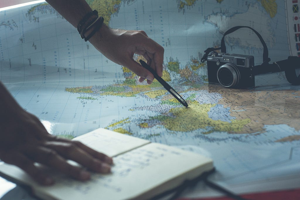 pointing on world map, a notebook and a camera
