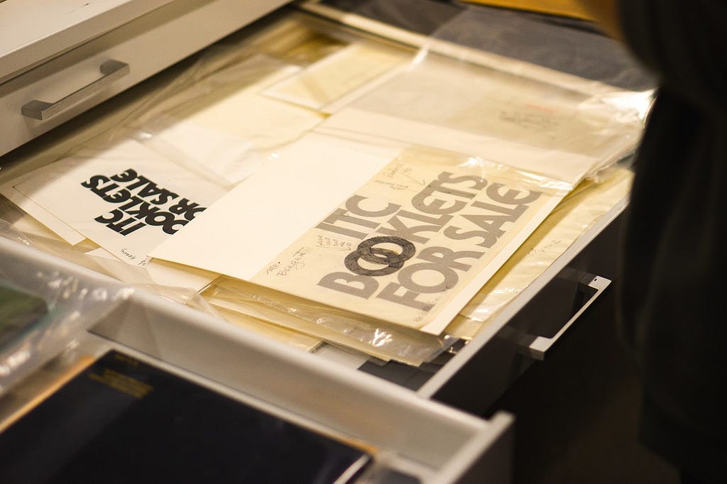 An open drawer containing typographic specimen sheets, with overlaid tracing paper and pencil markings.