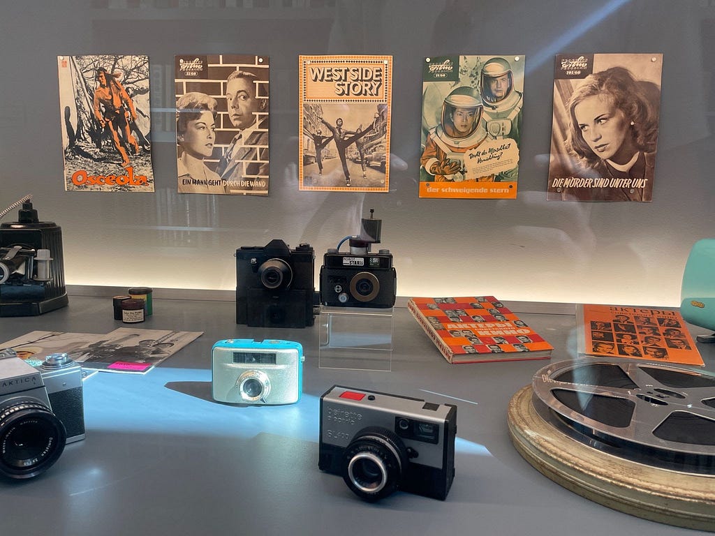 A display featuring a collection of cameras, film, and Polish zine-like leaflets from the Cold War era.