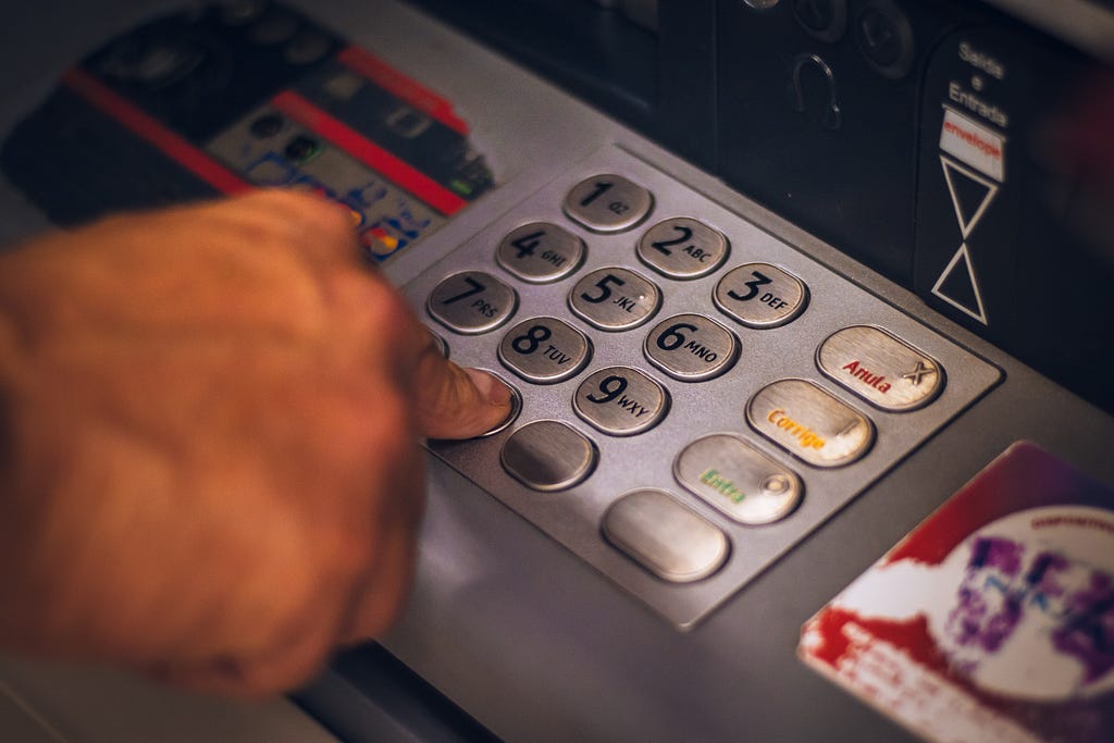 A hand punching in the code at an ATM, signifying bank deposit.