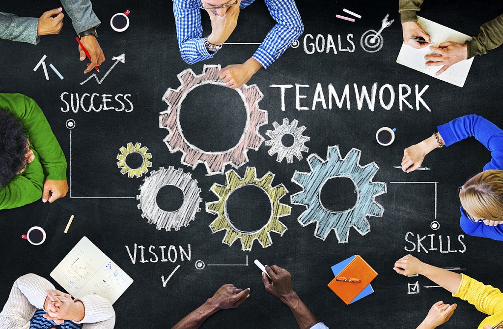 An illustration of various workplace values such as teamwork and vision along with people across a table brainstorming.