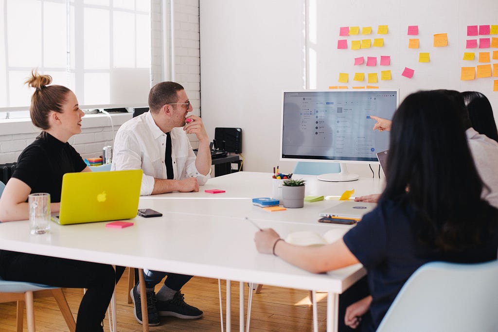 A group of people discussing something in front of the computer screen.