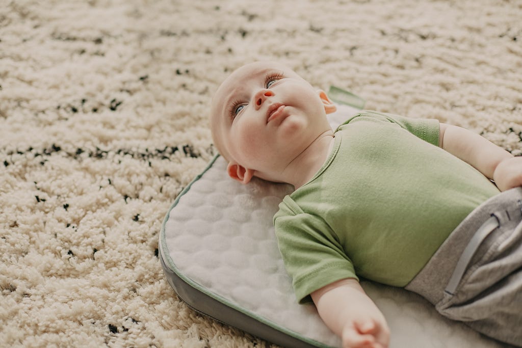 A baby contentedly lying on a mat