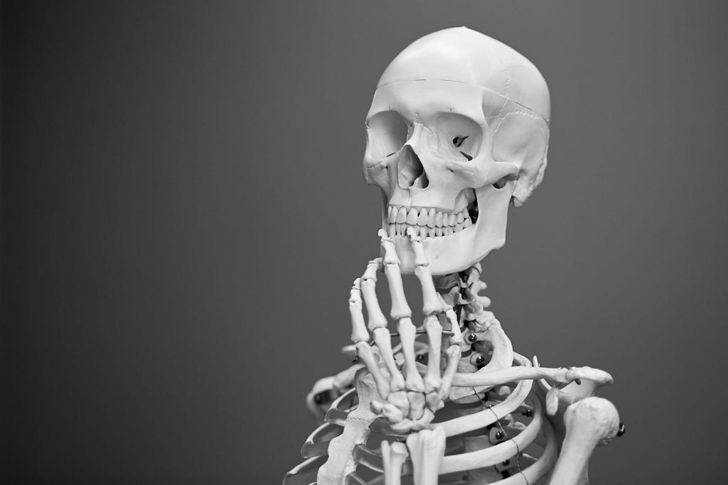 Human skeleton holding its hand to its chin in thought.