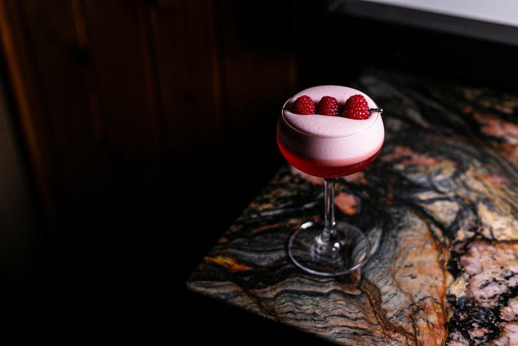 Clover Club cocktail with three raspberries resting atop the foam