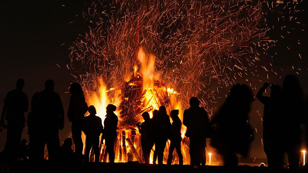 The silouette of people around a giant pyre