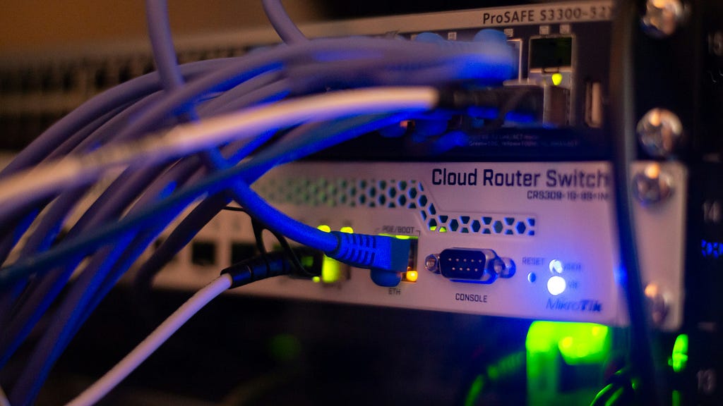 The back of a router, lit up with lots of cables attached to it