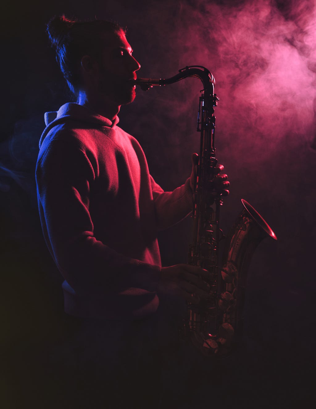 A man playing Saxophone in dark.