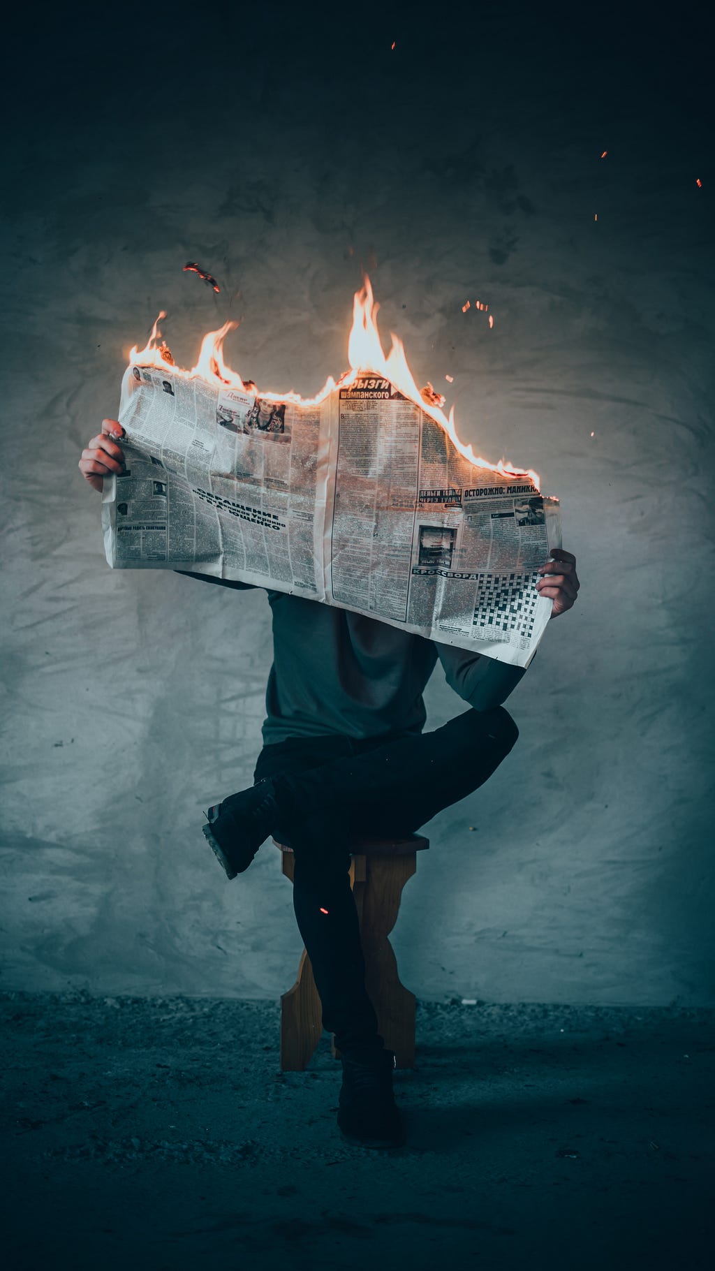 Man holding a newspaper that is on fire