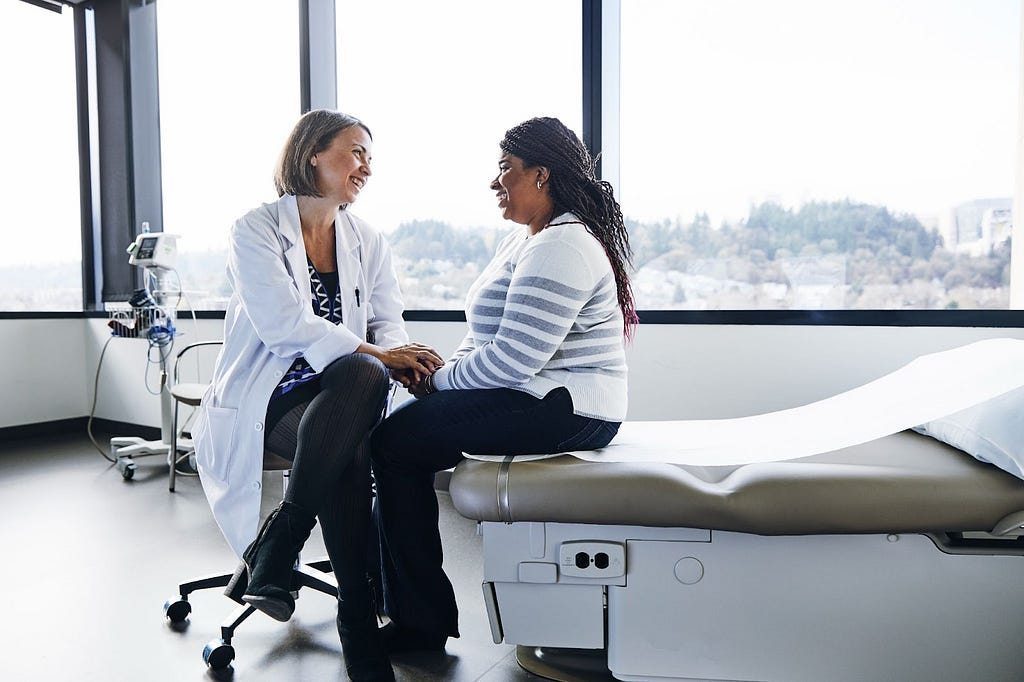 Female doctor smiling while talking to a patient in a hospital, reflecting the supportive role of genetic testing in cancer prevention