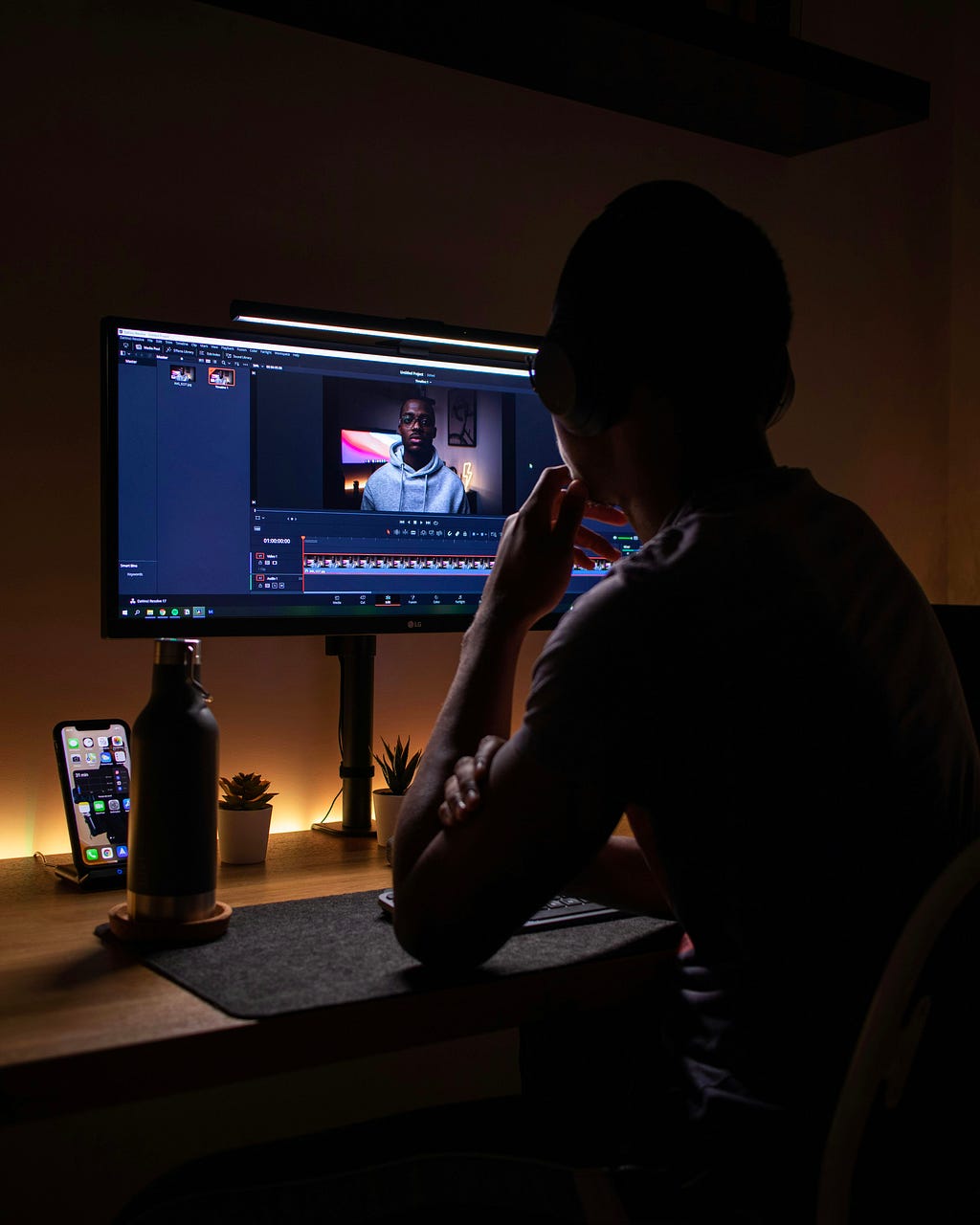 A Youtuber seated infront of a computer monitor editing a YouTube video