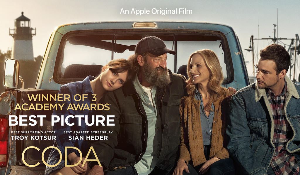 The family of four (Emilia Jones, Troy Kotsur, Marlee Matlin and Daniel Durant) featured in CODA sit on the bed of a truck, smiling and happy. “Winner of 3 Academy Awards: Best Picture, Best Supporting Actor (Troy Kotsur) and Best Adapted Screenplay (Sian Heder)” is captioned above the feature film title CODA