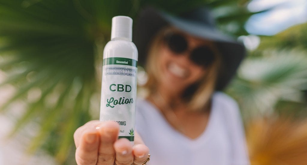 A woman holding a bottle of CBD lotion