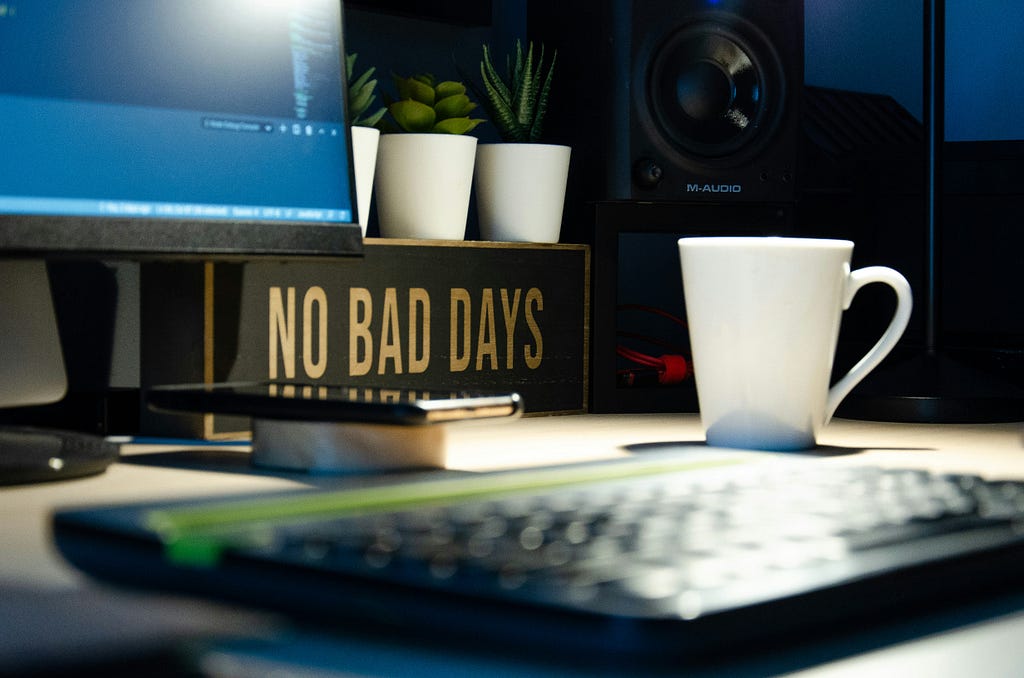 A work desk with the inspirational sign “no bad days” beside a coffee mug and some succulents.