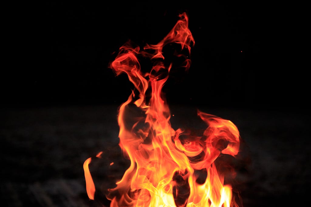 Photo of bright orange, red and yellow-white flames against a black background.