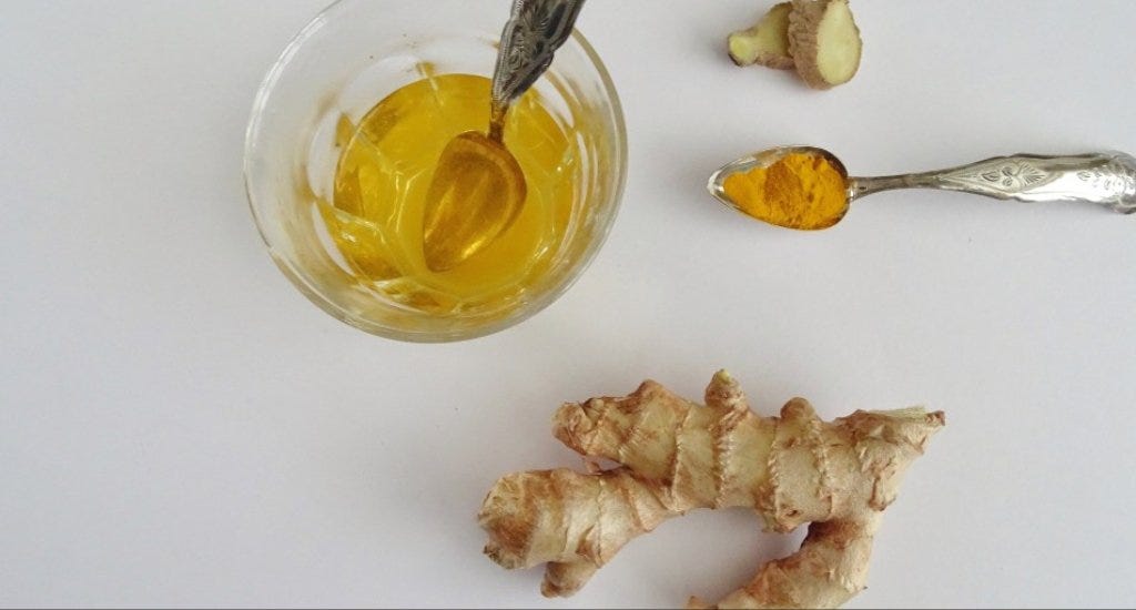 A piece of ginger next to a glass of tea