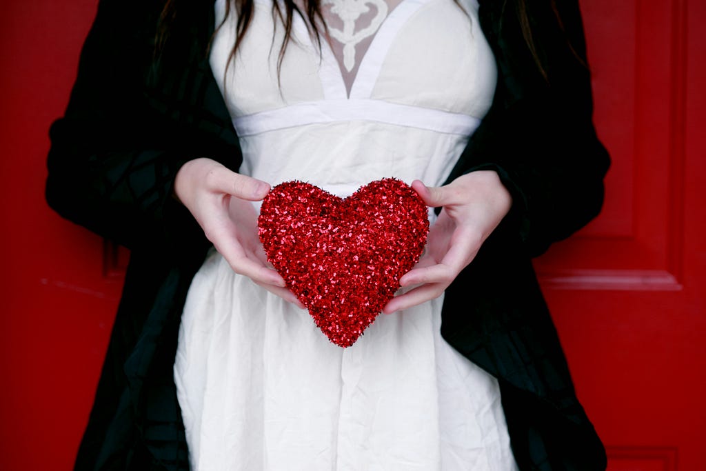 Photo of woman in a white dress holding a red heart
