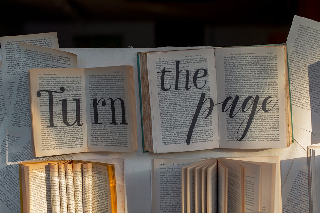 Numerous books open for reading, with “Turn the page” written across them.