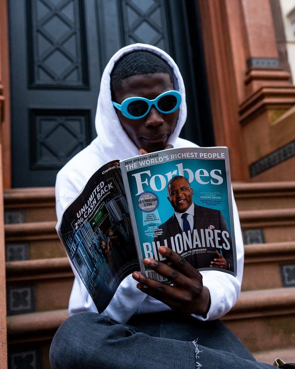 A man reading Forbes magazine with Billionaires on the cover