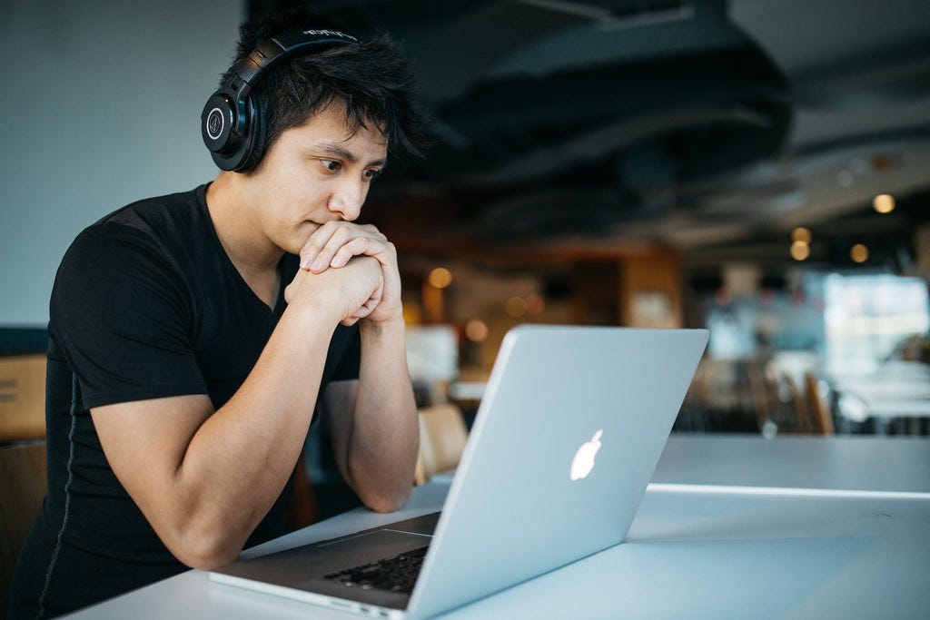 A gentleman wearing headphones and working on his laptop