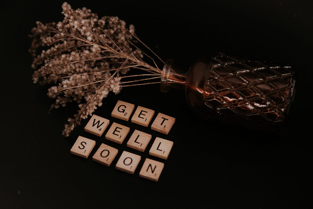 Scrabble tiles spelling get well soon on a black background