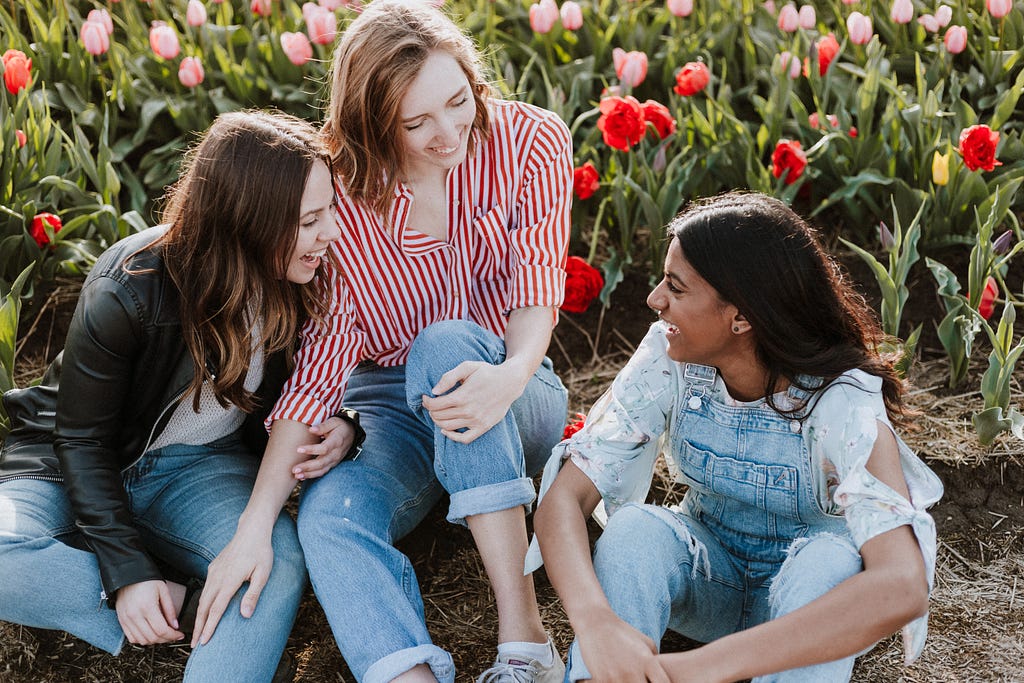 three girls laugh in a field of tulips