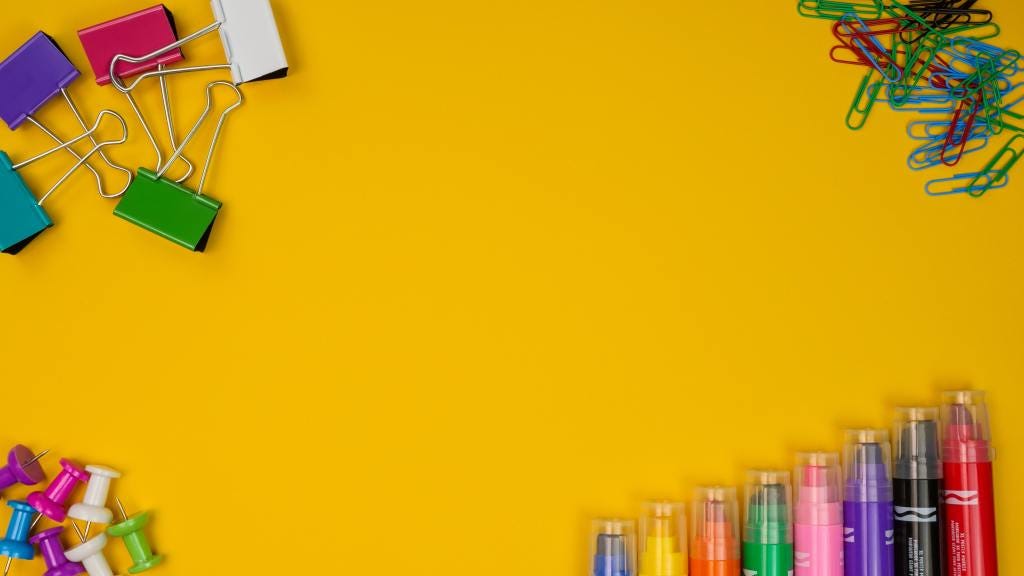 Pens, paperclips, pins and bulldog clips on gold yellow background.