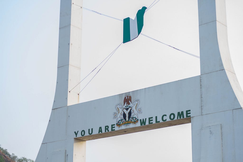 A welcome sign with the Nigerian flag and coat of arms