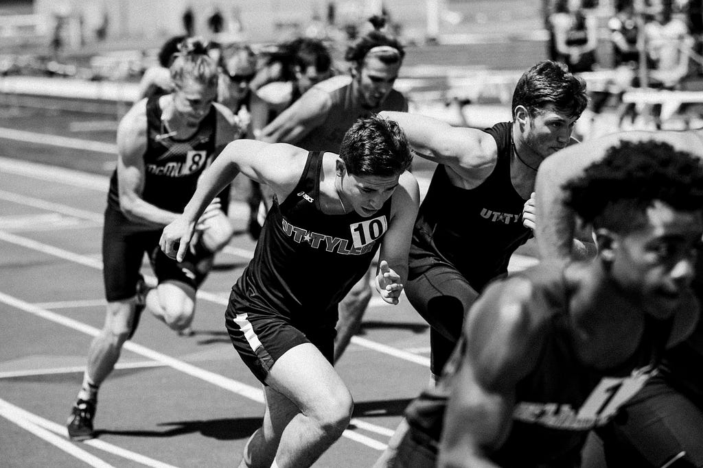 A group of athletes in a running race. You can see they are putting everything inot going as fast as they can.