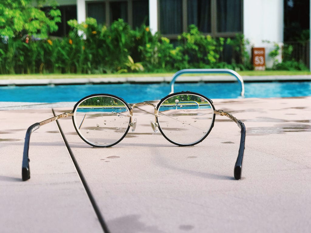 Spectacles lying on the side of a swimming pool.