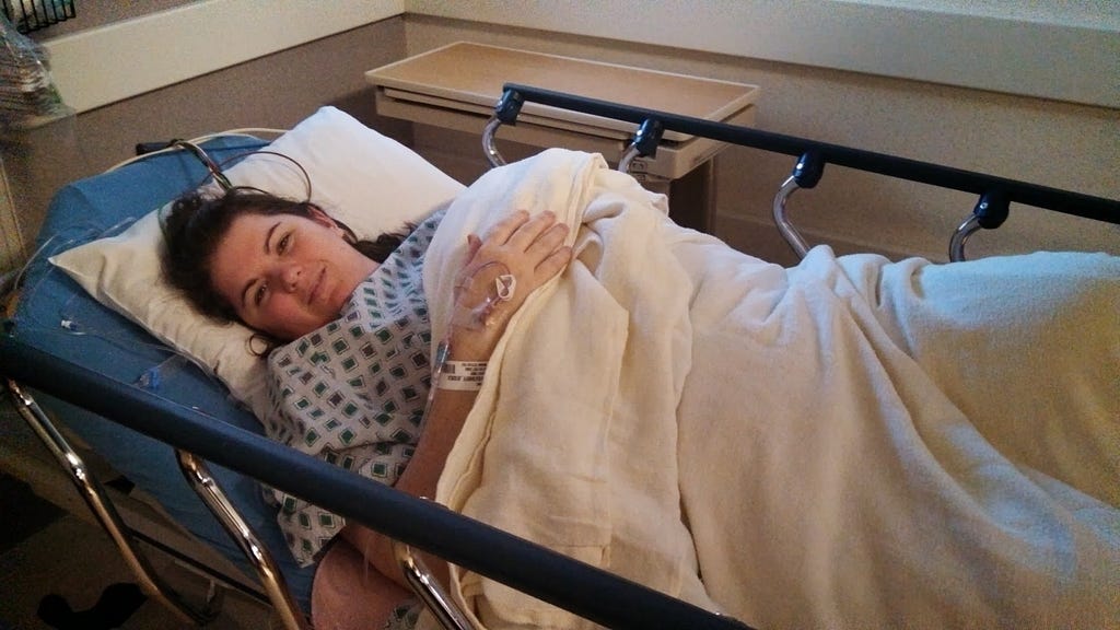 Photo of author, Jessica Reed, in a hospital bed, just waking from anesthesia after a bone marrow biopsy.