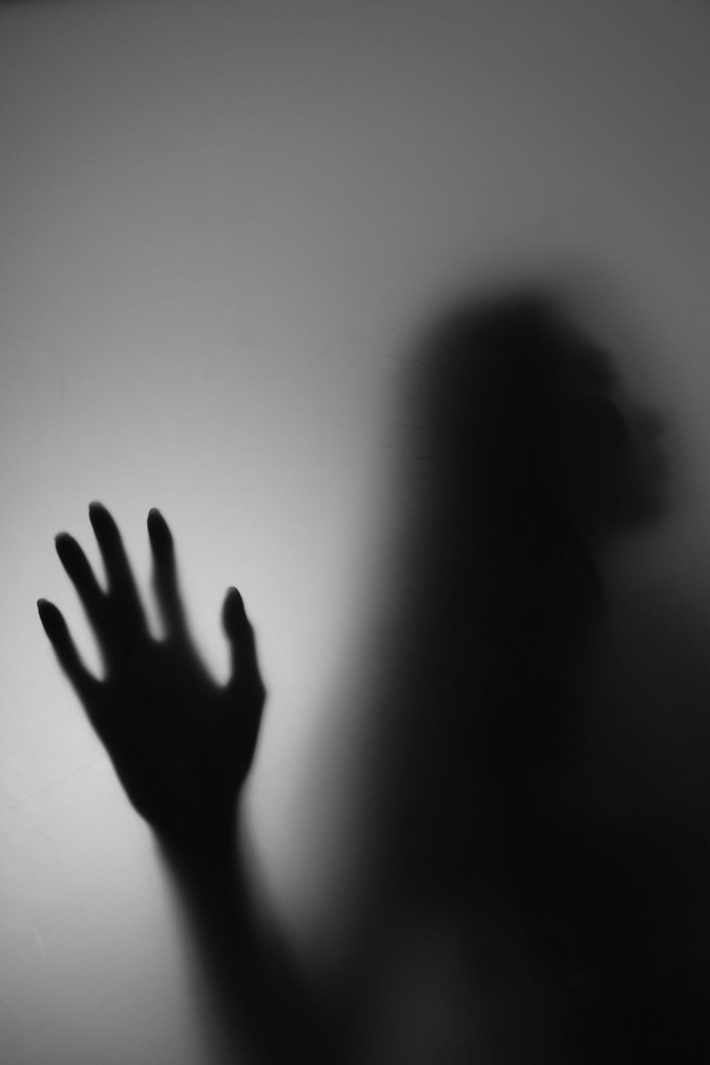 black and white photo of an eerie hand on a shadowed wall — psychiatric hospital