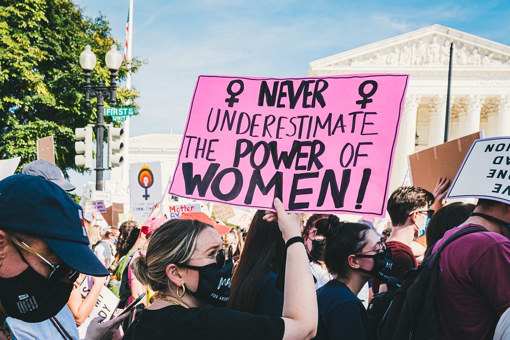 Mujer en protesta sosteniendo un cartel que dice “Nunca subestimes el poder de las mujeres”.