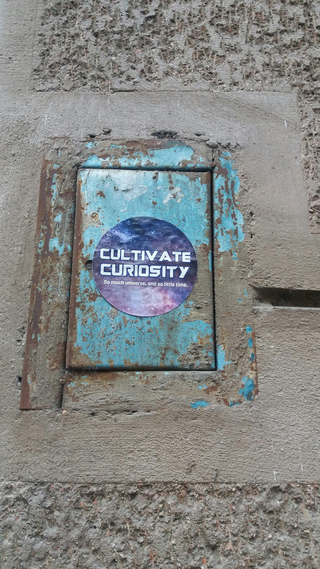 A blue iron plate, place on a floor having the purple text showing the image of curiosity.