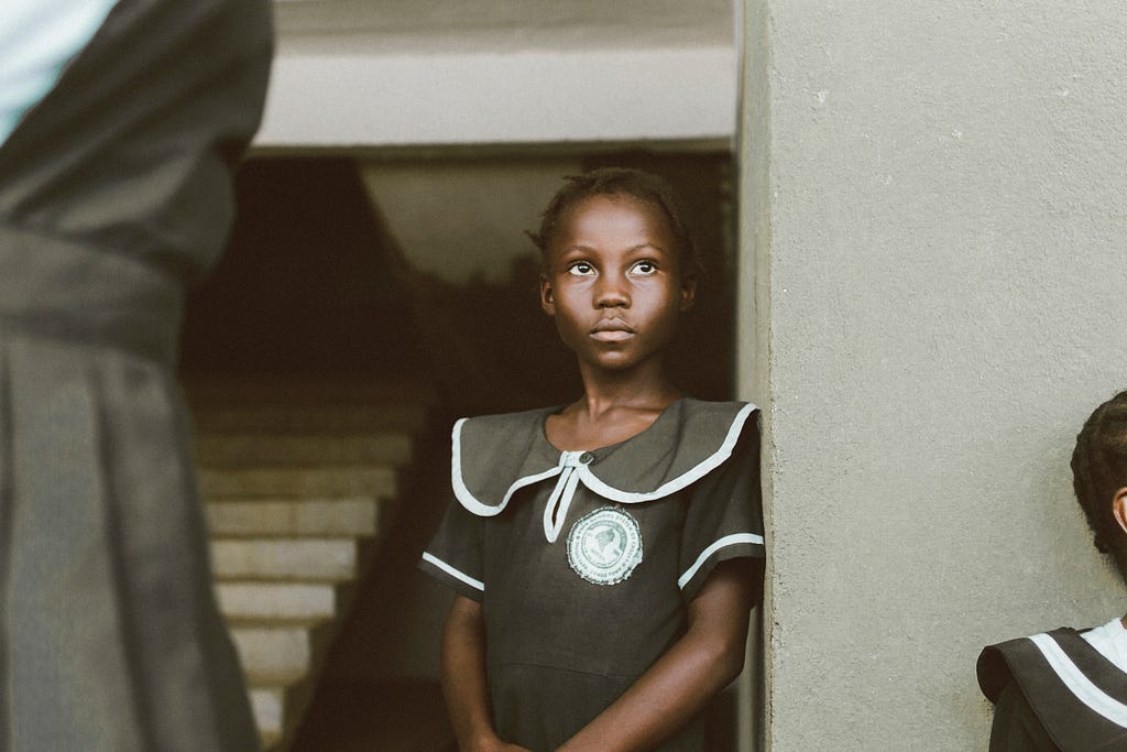 a young black girl stares straight ahead