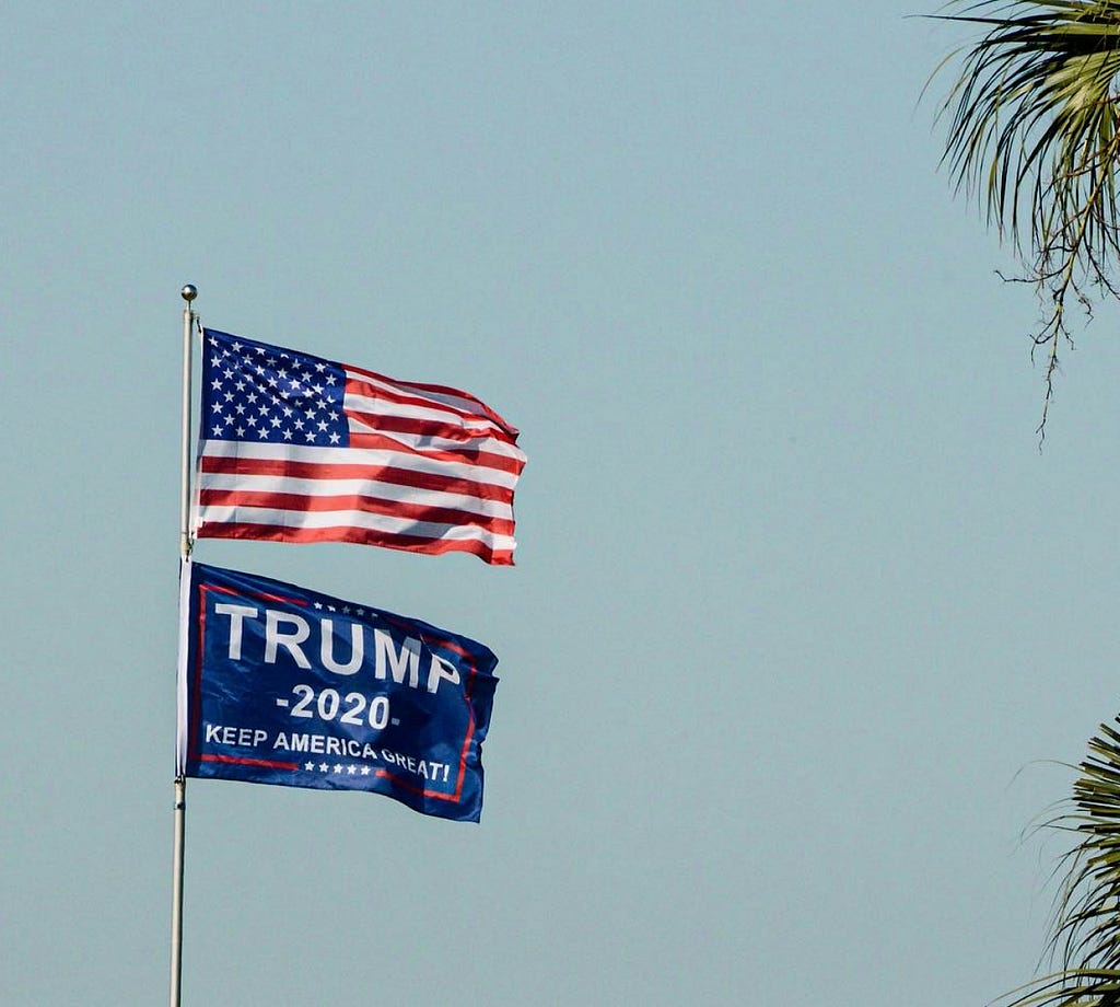 Flagpole with American flag above a Trump 2020 flag