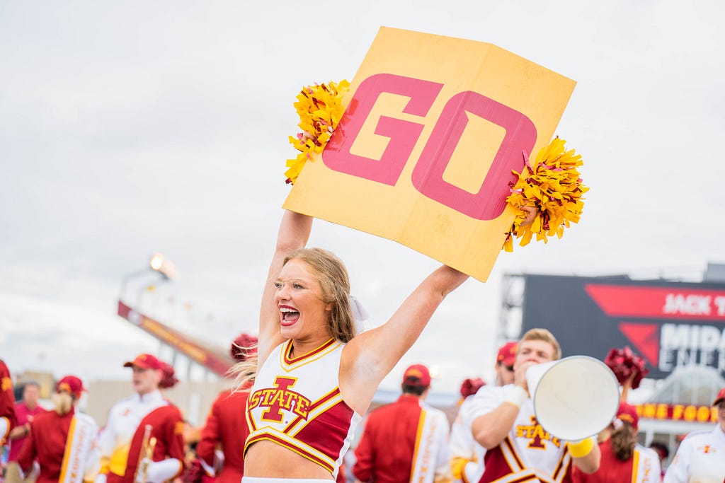 A cheerleader holding up a sign that says “go”.