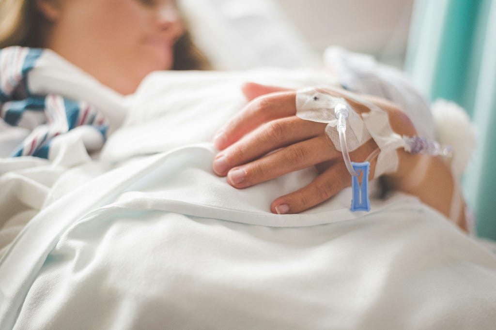 Woman in a hospital bed hooked up to IVs