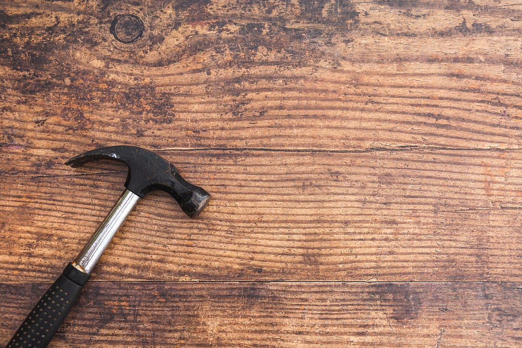 An image of a hammer sitting on a top of a piece of wood