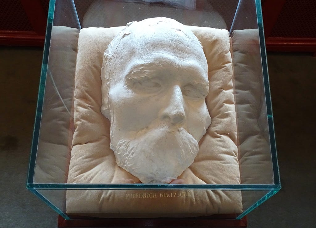 Death mask of German philosopher Friedrich Nietzsche on display in a glass case.